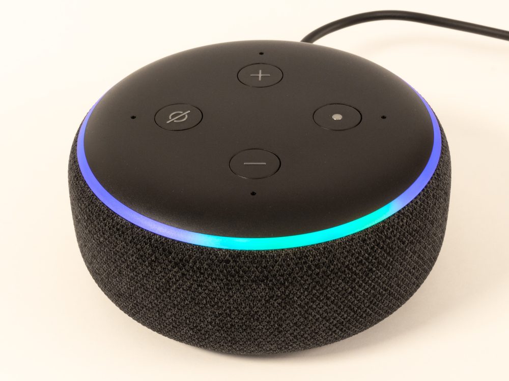 An Amazon Echo Dot smart speaker with its light ring glowing, ready for a voice command