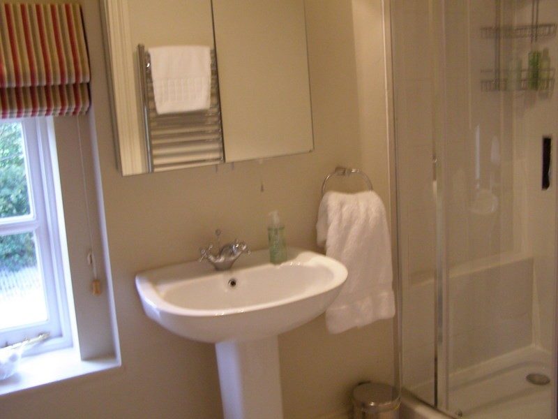 A clean, bright home bathroom with a sink and walk-in shower, set up for elderly bathroom safety
